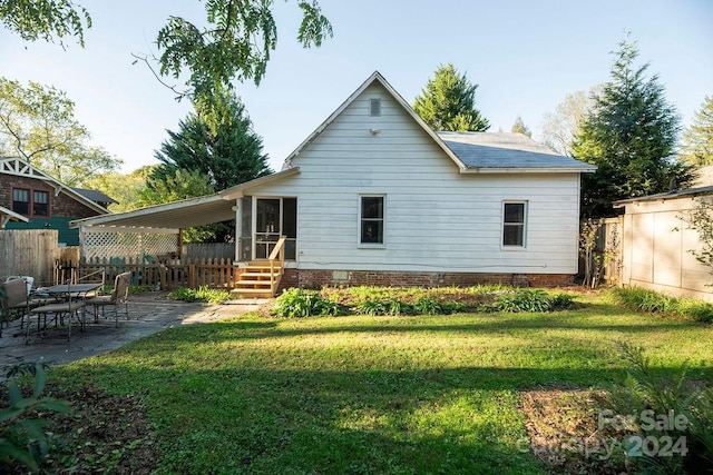 rear view of property featuring a patio and a lawn