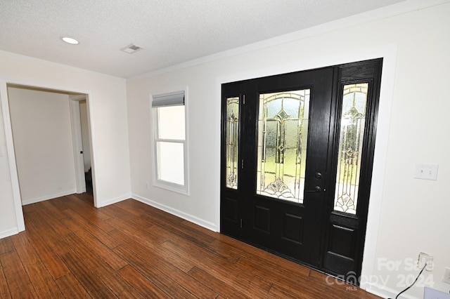 entryway with dark wood-type flooring, ornamental molding, and a textured ceiling