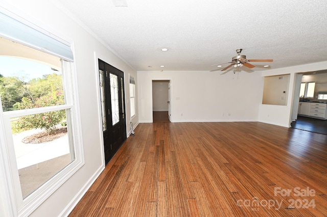 unfurnished living room with ceiling fan, a textured ceiling, and dark hardwood / wood-style floors