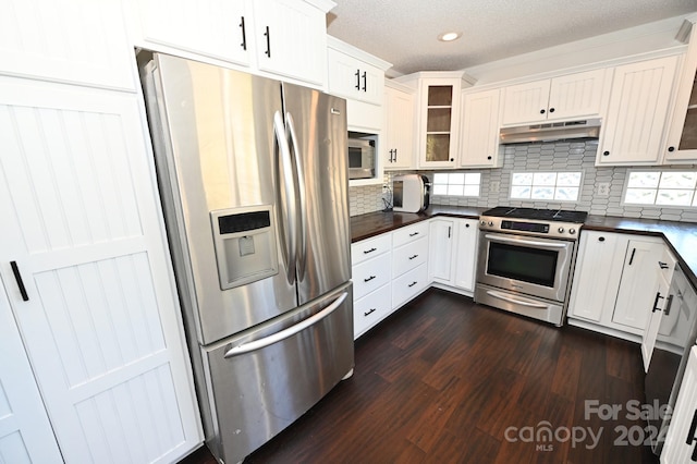 kitchen with dark hardwood / wood-style flooring, decorative backsplash, white cabinets, appliances with stainless steel finishes, and a textured ceiling