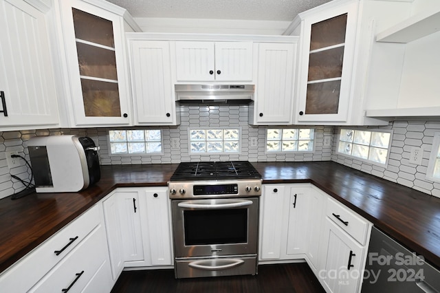 kitchen featuring extractor fan, stainless steel range, backsplash, and white cabinetry