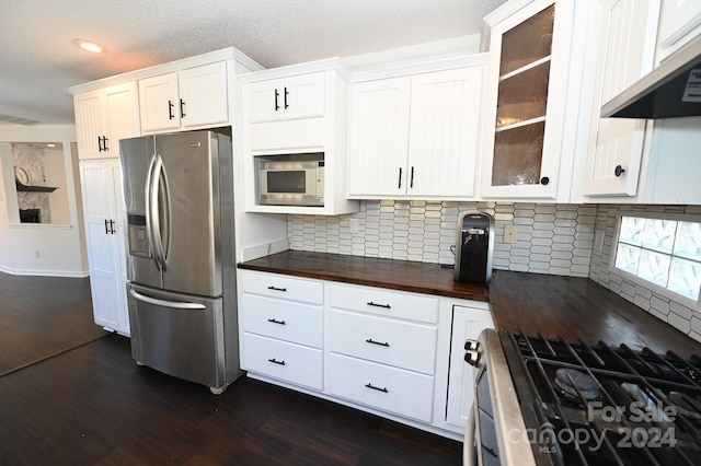 kitchen with extractor fan, wood counters, dark hardwood / wood-style floors, appliances with stainless steel finishes, and white cabinetry