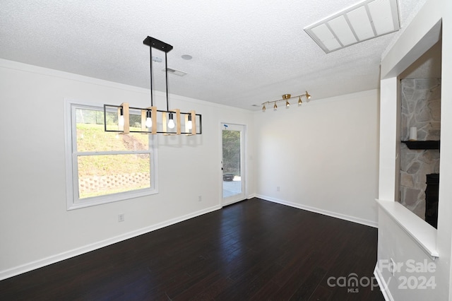 unfurnished dining area with a textured ceiling, plenty of natural light, and dark wood-type flooring