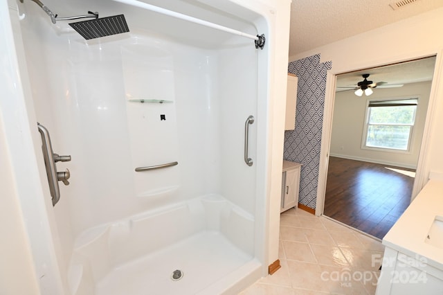 bathroom featuring ceiling fan, vanity, hardwood / wood-style floors, a shower, and a textured ceiling