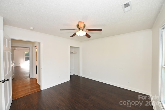 unfurnished room featuring ceiling fan, dark wood-type flooring, and a textured ceiling