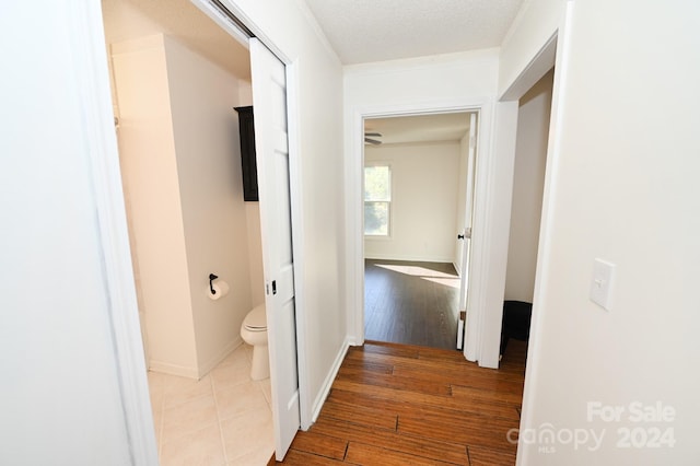 hall with a textured ceiling and light hardwood / wood-style flooring