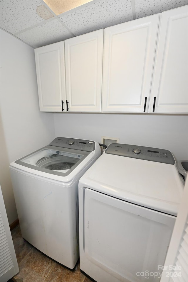 clothes washing area with dark tile patterned floors, cabinets, and washer and clothes dryer