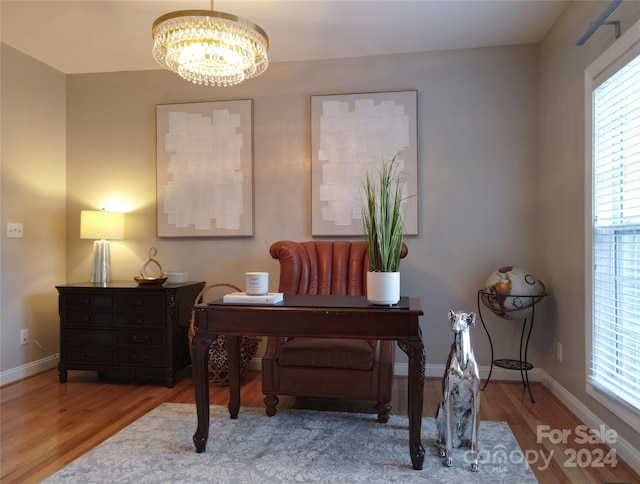 home office with a wealth of natural light, hardwood / wood-style floors, and a notable chandelier