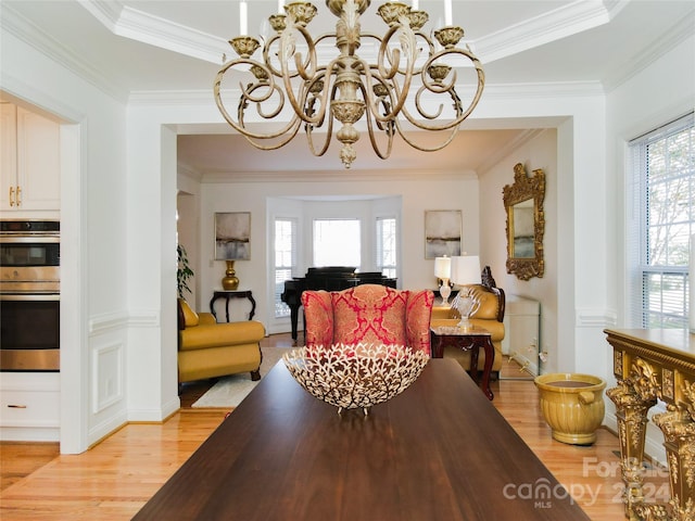 dining area with light hardwood / wood-style floors, ornamental molding, and a chandelier