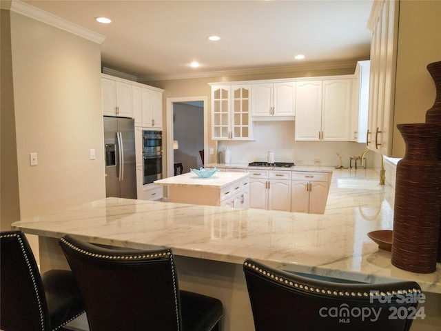 kitchen with kitchen peninsula, white cabinetry, a breakfast bar, and appliances with stainless steel finishes