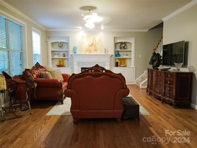 living room featuring built in shelves, wood-type flooring, and ornamental molding