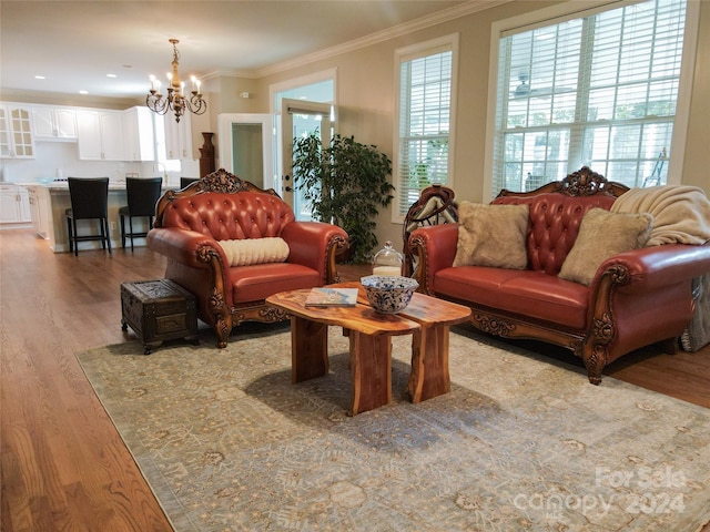 living room with light hardwood / wood-style flooring, ornamental molding, and a notable chandelier