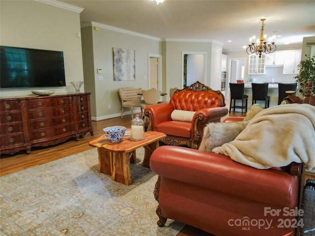 living room with light hardwood / wood-style floors, ornamental molding, and a chandelier