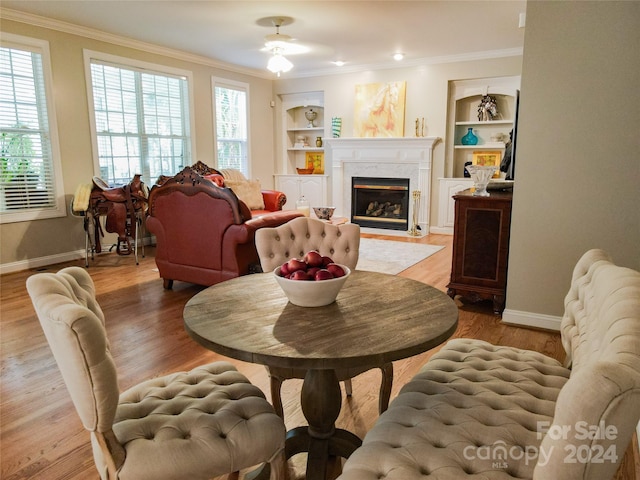 living room featuring plenty of natural light, a high end fireplace, built in features, and light wood-type flooring