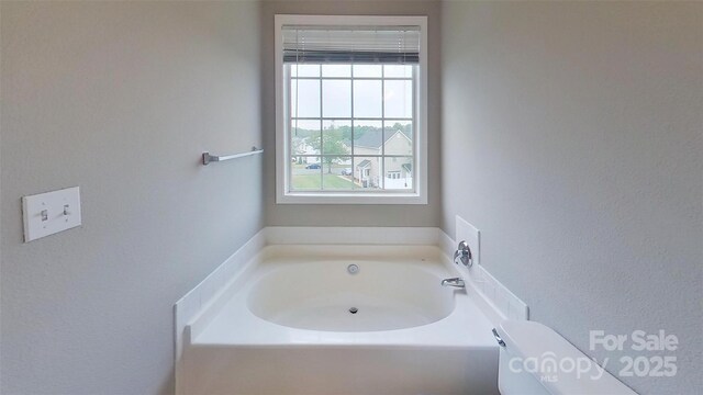 8403 Spirea Ct, Charlotte, NC 28215 - bathroom featuring a garden tub, toilet, and a textured wall