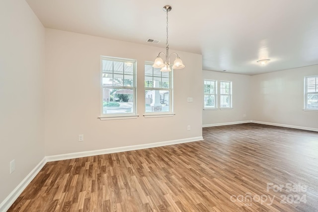 spare room featuring wood-type flooring and a chandelier