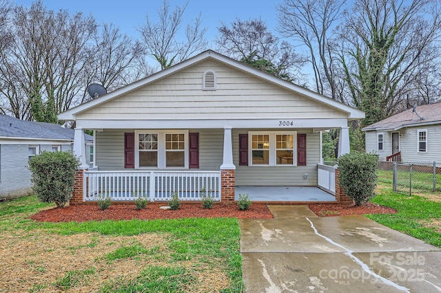 view of front of property with covered porch, a front yard, and fence