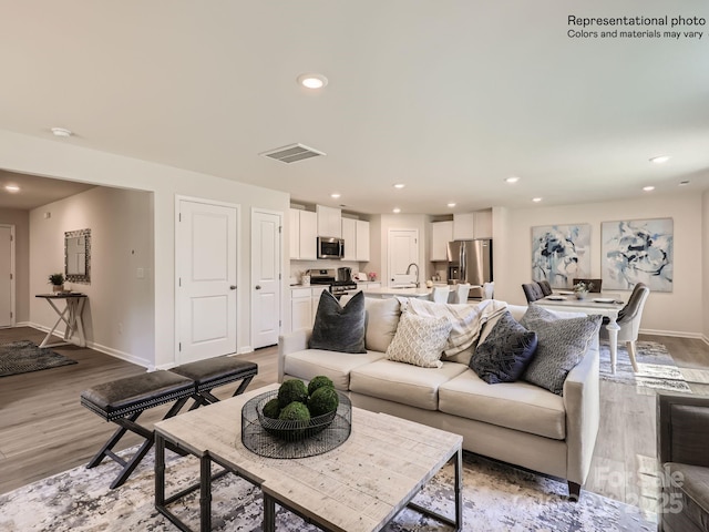 living room featuring sink and light hardwood / wood-style floors