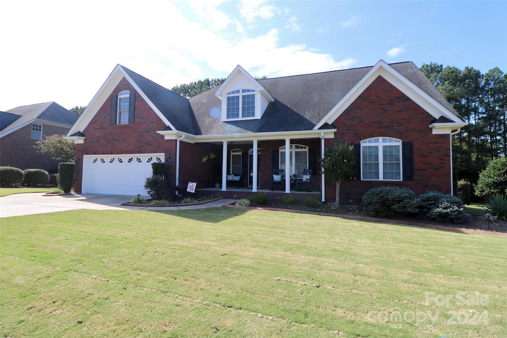 view of front facade featuring a front yard, a garage, and a porch