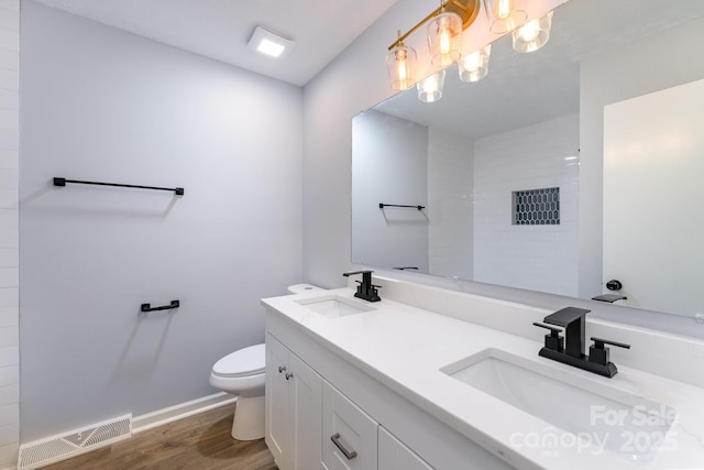bathroom featuring a sink, toilet, visible vents, and wood finished floors