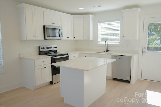 kitchen featuring a kitchen island, sink, stainless steel appliances, and white cabinets