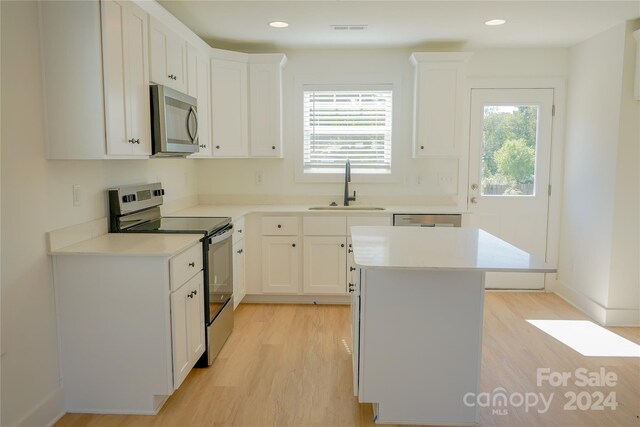 kitchen with appliances with stainless steel finishes, sink, a center island, and white cabinetry