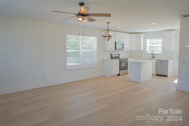 kitchen featuring appliances with stainless steel finishes, light wood-type flooring, white cabinetry, and a center island