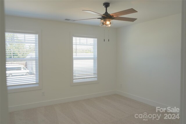 carpeted spare room featuring ceiling fan and a healthy amount of sunlight