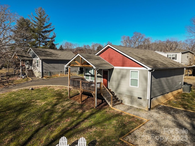 rear view of property with central AC unit and a lawn