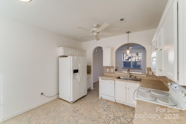 kitchen with ceiling fan, light countertops, arched walkways, white appliances, and a sink