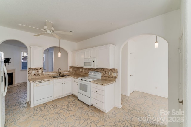 kitchen with a sink, white appliances, arched walkways, decorative backsplash, and ceiling fan