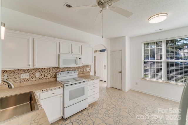 kitchen featuring decorative backsplash, white appliances, white cabinetry, and a sink