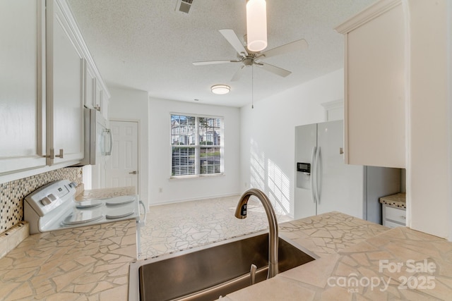 kitchen featuring white appliances, visible vents, a sink, light countertops, and tasteful backsplash