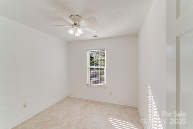 unfurnished room with baseboards, visible vents, ceiling fan, a textured ceiling, and light colored carpet