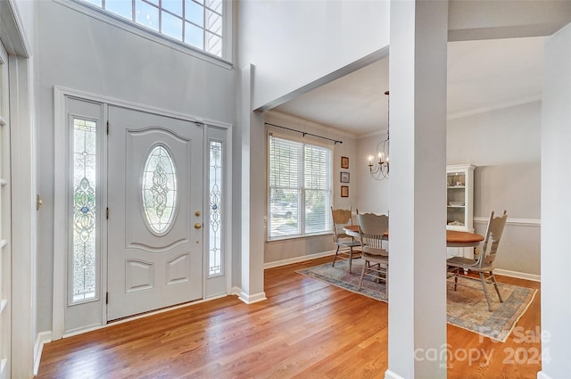 entrance foyer featuring ornamental molding, light wood-type flooring, and a chandelier