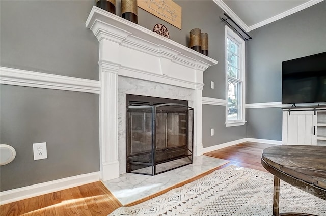 living room with a barn door, ornamental molding, hardwood / wood-style flooring, and a fireplace