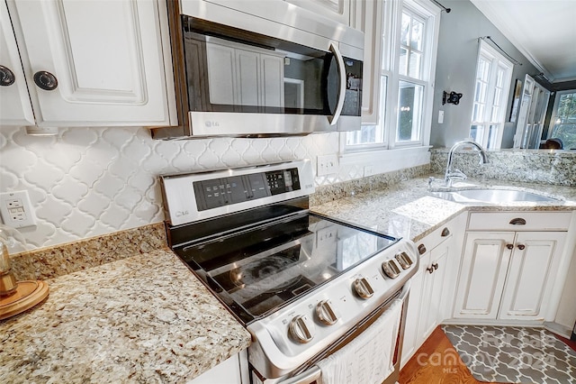 kitchen featuring appliances with stainless steel finishes, crown molding, white cabinetry, and sink