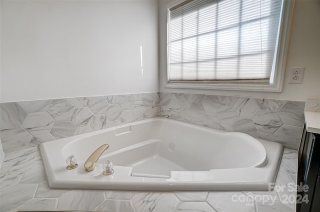 bathroom featuring vanity and tiled bath