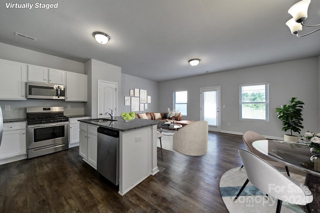 kitchen with stainless steel appliances, a center island with sink, sink, and white cabinetry