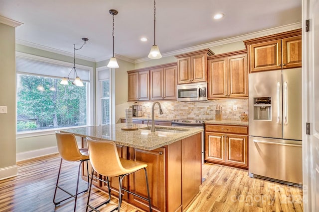 kitchen featuring light stone countertops, a kitchen island with sink, stainless steel appliances, sink, and light hardwood / wood-style floors