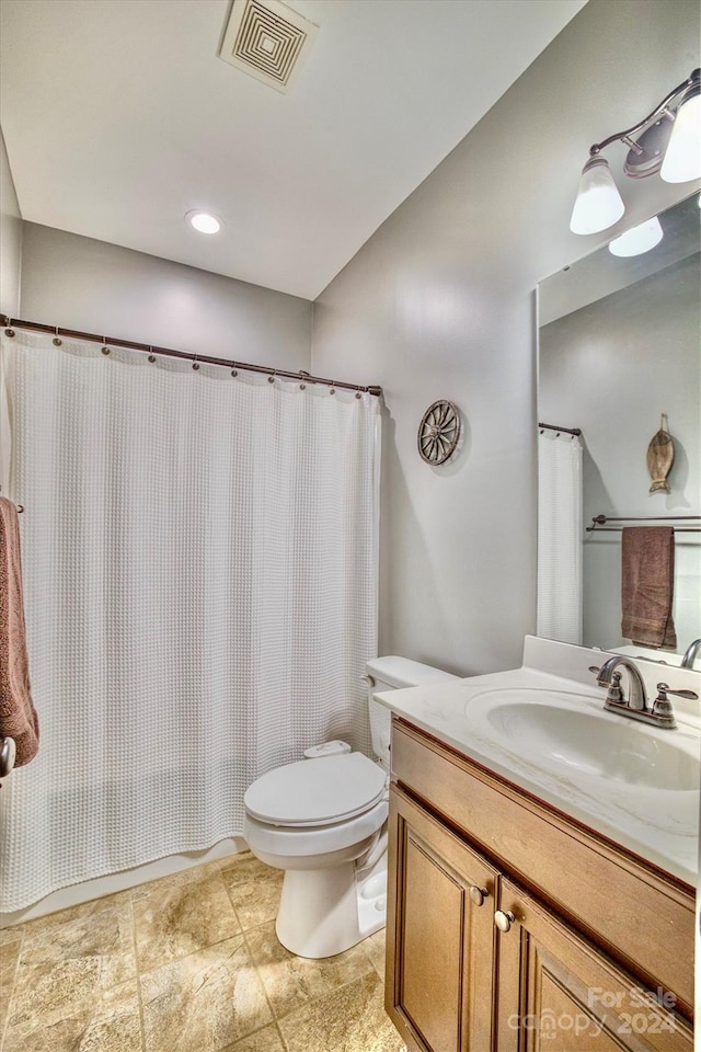 bathroom with curtained shower, vanity, and toilet