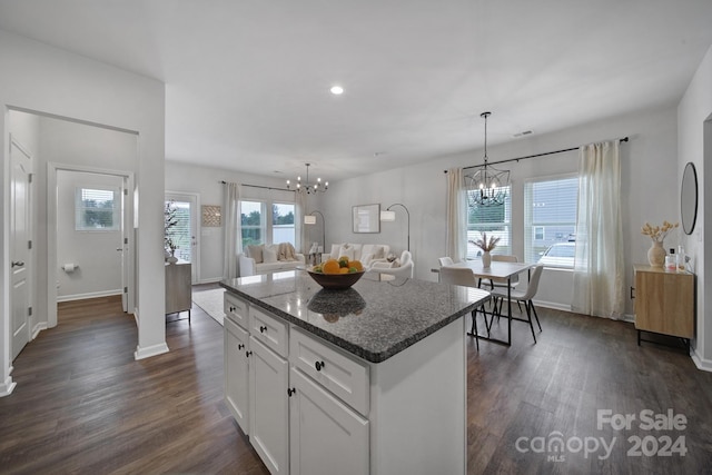 kitchen featuring white cabinetry, a center island, dark stone counters, and a wealth of natural light