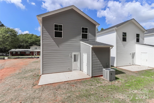 rear view of property with a yard, a patio, and central air condition unit