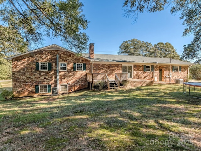 rear view of house featuring cooling unit, a trampoline, a yard, and a wooden deck