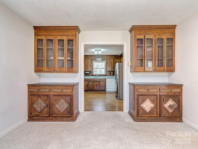 kitchen with dishwasher, sink, a textured ceiling, light colored carpet, and stainless steel refrigerator