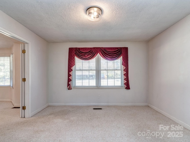 carpeted empty room featuring a textured ceiling