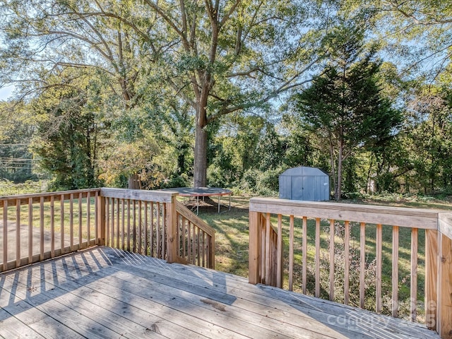 wooden deck featuring a storage shed and a trampoline