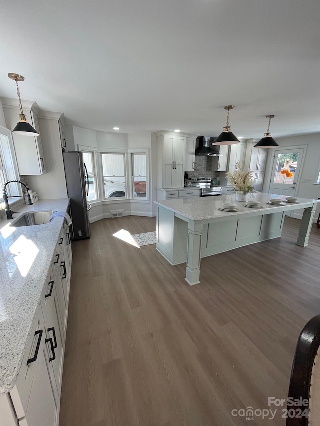 kitchen with appliances with stainless steel finishes, hanging light fixtures, a center island, and light hardwood / wood-style flooring