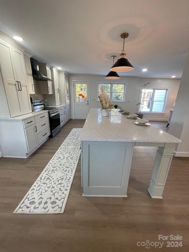 kitchen with wall chimney exhaust hood, light stone countertops, white cabinets, and electric stove