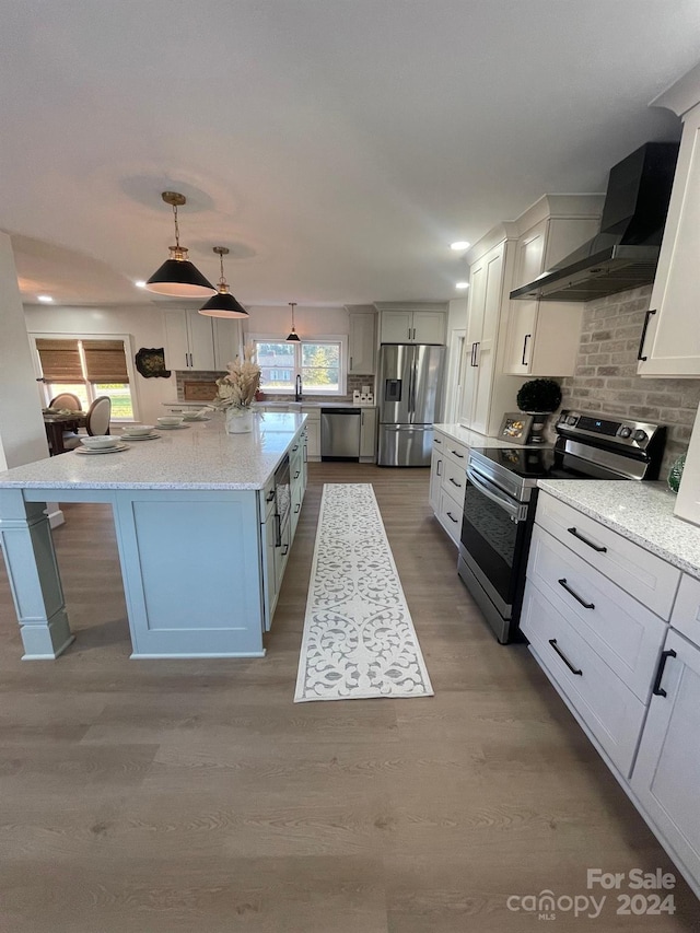 kitchen featuring a kitchen island, hanging light fixtures, stainless steel appliances, and light hardwood / wood-style flooring